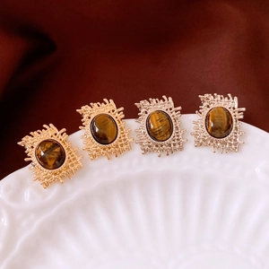 Macro detail of vintage gold and silver oval tiger eye earrings on white ceramic