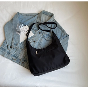 Detail of minimalist black canvas crossbody bag with adjustable strap and front zipper pocket