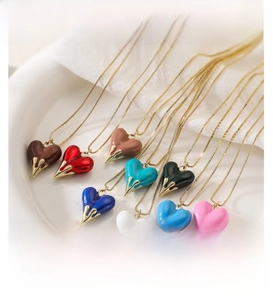 Close-up of colorful heart pendants with liquid gold finish in a ceramic display tray