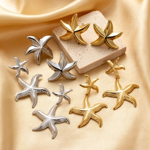 Minimalist stainless steel starfish earrings in gold and silver on silk fabric