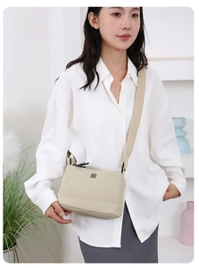Gros plan du sac bandoulière beige en nylon avec sangle réglable et détail de logo métallique