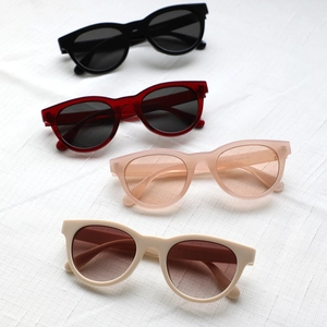 Chic round retro sunglasses in black red nude and off-white colors on white fabric