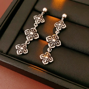 Macro shot of vintage silver floral drop earrings with a textured embossed finish