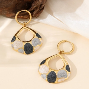 Detailed view of teardrop earrings with marble texture on silk and wood background