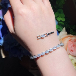 Detailed close-up of oval-cut zircon tennis bracelet with silver finish on a female wrist