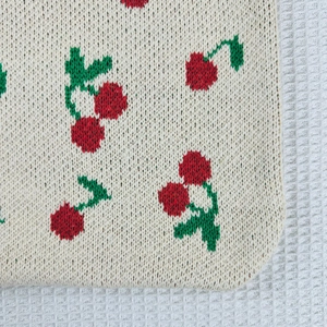 Close-up of knit tote bag showing detailed cherry patterns and woven texture