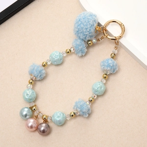 Detail of light blue fluffy pompoms and golden spring clasp on a stylish bag charm