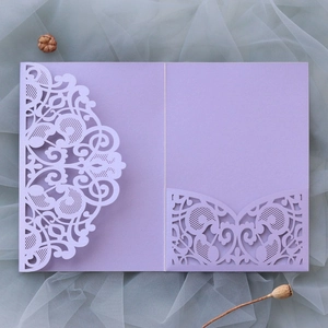 Close-up of laser-cut lavender purple wedding invitation with intricate hollow floral patterns