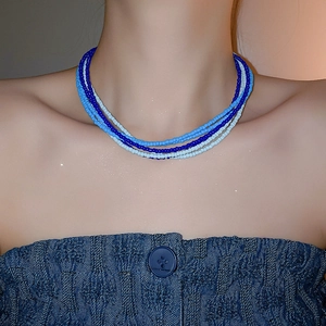 Detail of multi-strand bohemian blue seed bead choker necklace on model's neck
