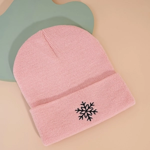 Détail d'un bonnet en maille rose avec broderie de flocon noir et bord à revers