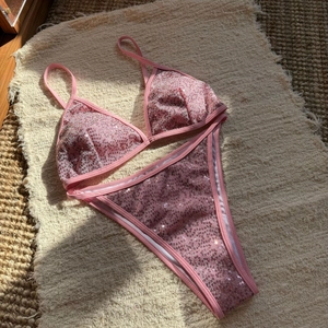 Macro detail of pink sequin bikini set showing reflective textures on a woven mat