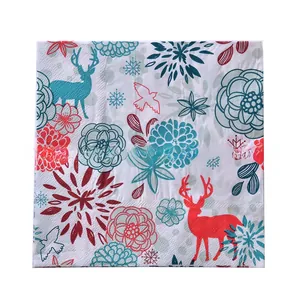 Detail of Christmas paper napkins with red elk and teal snowflake prints and dot embossing