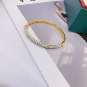 Irregular gold titanium steel bracelet with pavé diamonds on a stylish background