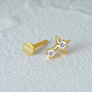 Macro view of gold S925 sterling silver cross star cartilage stud with clear gemstones