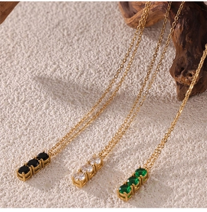 Detailed view of gold necklaces featuring three vertically aligned zircons in black, white, and emerald