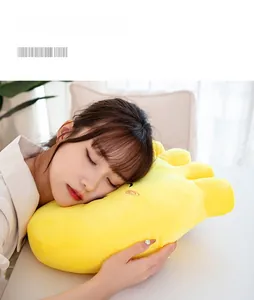 Close-up of soft yellow plush foot pillow with cartoon embroidery used by a model