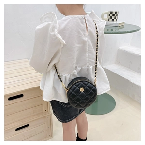Girl wearing black quilted leather crossbody bag with camellia detail and gold chain strap