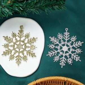 Glittery gold and silver snowflake ornaments for Christmas tree decor on green backdrop