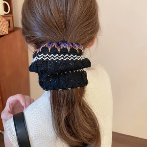 Détail d'un chouchou en dentelle noire avec broderie colorée porté dans un cadre domestique