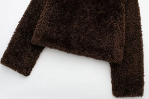 Detailed view of the thick brown faux fur texture and stitching on the hem and cuff