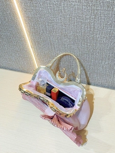 Pink silk evening bag interior capacity showing makeup items and gold metal handle