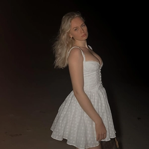 Detail of white embroidered mini dress featuring low-cut back and A-line silhouette