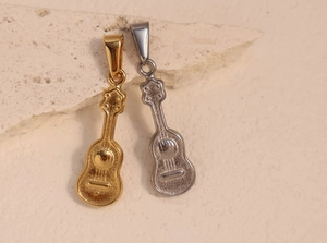 Detailed view of guitar pendants in gold and silver finish on a textured stone