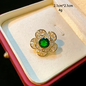 Macro view of emerald green gemstone brooch in gold flower shape with zircon petals