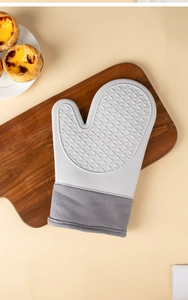 Detail of gray heat-resistant oven mitt with non-slip silicone texture on wood board