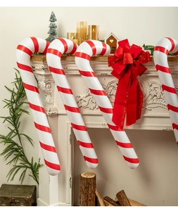 Set of inflatable Christmas candy canes with red bow displayed on a festive fireplace mantle