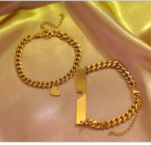 Detail of gold heart and rectangle plate bracelets on soft pink satin fabric background