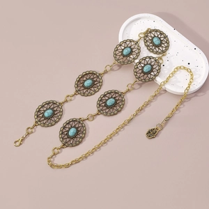 Detail of bohemian gold waist chain featuring turquoise resin stones and floral metalwork