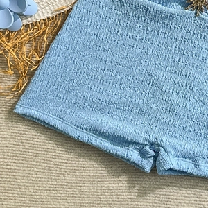 Close-up of light blue smocked fabric texture on a slim fit one-piece swimsuit