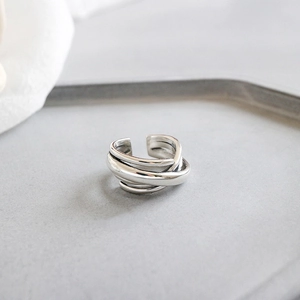 Macro detail of silver multi-layer winding ring with adjustable open design on fabric