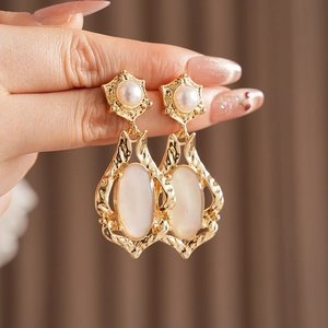 Détails de boucles d'oreilles vintage dorées avec étoiles perlées et nacre ovale