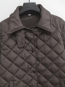 Detail of dark brown quilted jacket showing collar, buttons, and diamond pattern texture