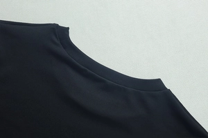 Gros plan du col rond montrant la texture en maille fine de ce haut noir élégant