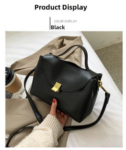 Detail of a black leather handbag with a gold square lock and adjustable shoulder strap