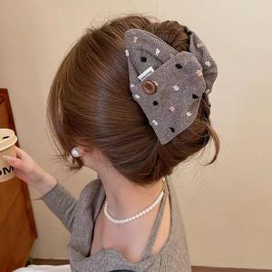 Detail of grey dotted fabric bow hair clip with vintage brown button and Hand Made label