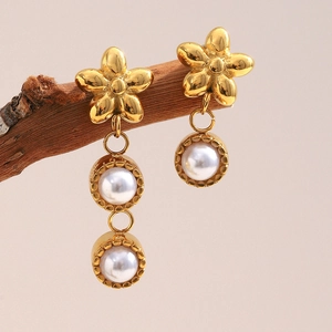 Detail of asymmetrical 18K gold-plated floral earrings with pearls on a branch