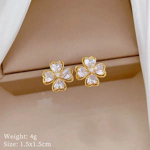 Close-up of gold clover earrings with white zircon on a jewelry box, size 1.5x1.5cm