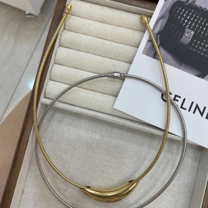 Close-up of gold and silver snake chain necklaces with sleek curved metal pendants