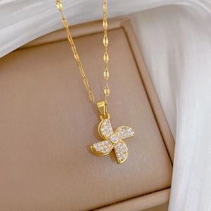 Close-up of a rotating gold windmill pendant necklace with white zircons on a jewelry box