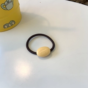 Close-up of cream oval bead on a brown elastic hair tie with a high-stretch fiber cord