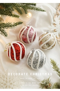 Glitzernde Weihnachtskugeln im Vierer-Set auf weißem Stoff mit festlichen Kiefernzweigen Deko