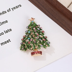 Detailed macro shot of a green enamel Christmas tree brooch with colorful rhinestones