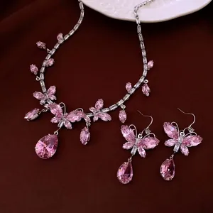 Elegant silver necklace and earring set with pink teardrop crystals on velvet background
