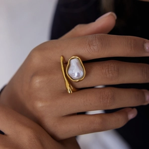 Close-up of elegant 18K gold stainless steel ring with a large baroque pearl on finger