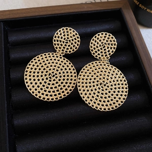 Detailed macro view of gold hollow mesh woven round drop earrings on black velvet
