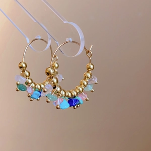 Detailed close-up of handmade gold hoops with colorful natural stones and beads